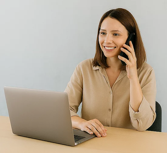 Frau am Telefon im Gespräch über ein TYPO3-Webprojekt, Laptop auf dem Tisch